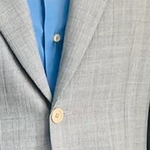 Botón nacarado y su ojal en una chaqueta gris